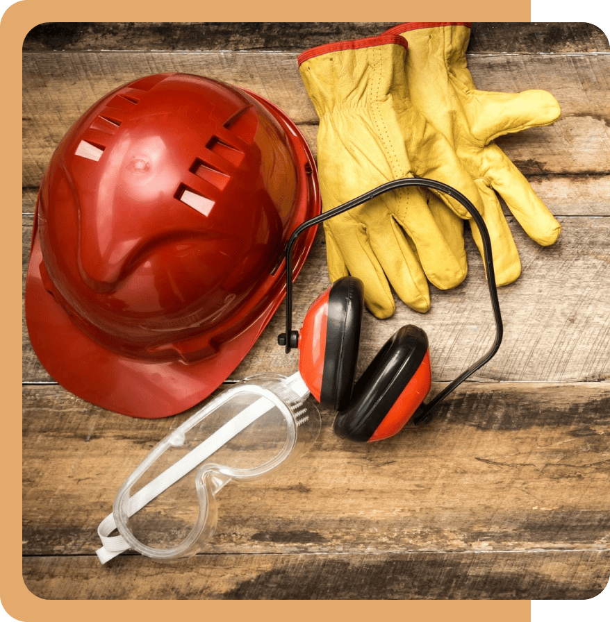 Safety gear including helmet, gloves, goggles, and earmuffs on wood.